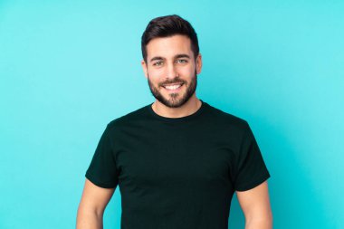 Beyaz tenli yakışıklı adam mavi arka planda izole edilmiş gülüyor.