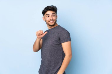 Münferit bir geçmişi olan Arap yakışıklı bir adam bir ürünü sunmak için kenarı işaret ediyor.