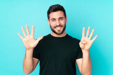 Beyaz tenli yakışıklı adam mavi arka planda izole edilmiş dokuz parmaklı sayıyor.