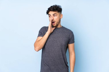 Soyutlanmış arka planda yaşayan yakışıklı Arap bir adam. Yan tarafa bakarken sürpriz bir jest yapıyor.