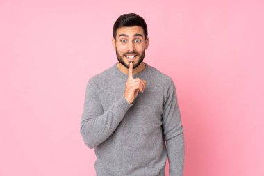 Kafkasyalı yakışıklı adam izole edilmiş arka planda sessizlik işareti gösteriyor. Parmağını ağzına sokuyor.