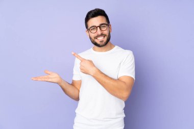 Kafkasyalı yakışıklı, izole edilmiş arka plan üzerinde. Avucunun içinde hayali bir ilan tutuyor.