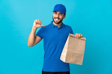 Mavi arka planda sakallı teslimatçı gururlu ve kendini beğenmiş.