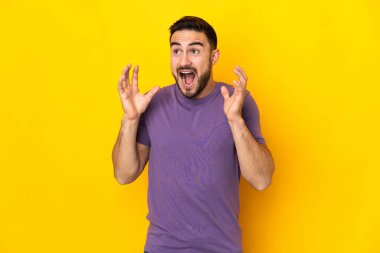 Sarı arka planda yalıtılmış, yüzü şaşırmış, beyaz, yakışıklı genç bir adam.