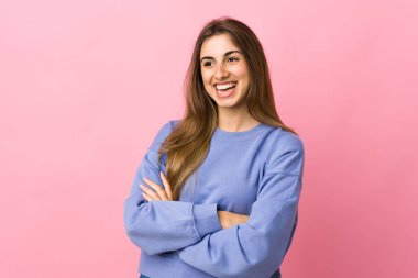 Soyutlanmış pembe arka planda genç bir kadın mutlu ve gülümsüyor