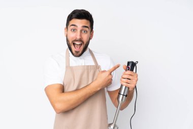 Beyaz arkaplanda izole edilmiş el blenderi kullanan adam parmağını yana doğru gösteriyor.