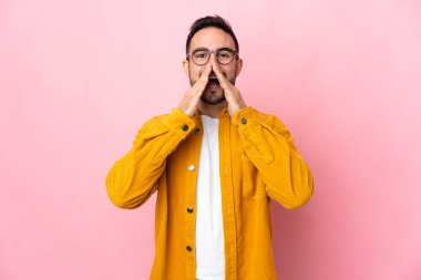 Beyaz tenli yakışıklı adam pembe arka planda izole edilmiş bağırıyor ve bir şeyler söylüyor.