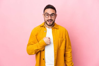 Pembe arka planda yalıtılmış beyaz, yakışıklı, şaşırtıcı bir yüz ifadesi olan genç adam.