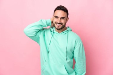 Beyaz tenli yakışıklı adam pembe arka planda izole edilmiş gülüyor.