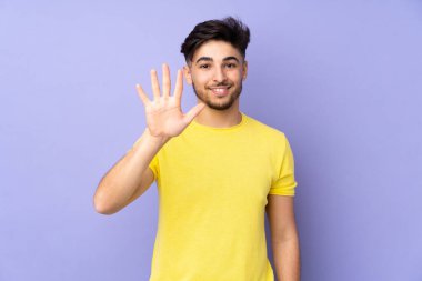 İzole edilmiş geçmişi olan Arap yakışıklı bir adam parmaklarıyla beşi sayıyor.