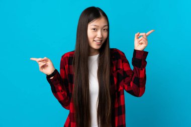 Soyutlanmış mavi arka planda genç bir Çinli kız parmak uçlarını işaret ediyor ve mutlu