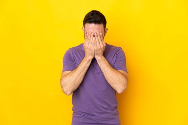 Sarı arka planda izole edilmiş, yorgun ve hasta bir ifadeyle genç, beyaz, yakışıklı bir adam.