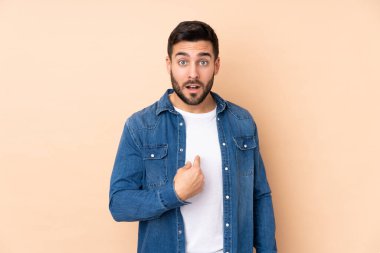 Beyaz tenli yakışıklı adam bej arka planda izole edilmiş. Kendini işaret ediyor.