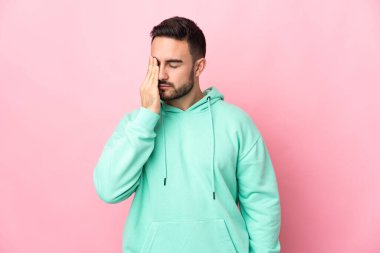 Pembe arka planda yalnız ve başı ağrıyan beyaz, yakışıklı genç bir adam.