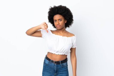 Beyaz arka planda izole edilmiş genç Afrikalı Amerikalı kadın, olumsuz ifadeyle baş parmağını aşağı gösteriyor.