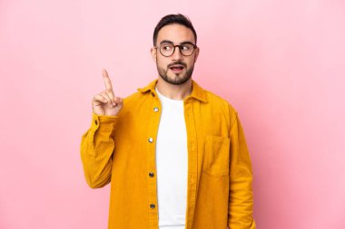 Pembe arka planda soyutlanmış beyaz, yakışıklı bir adam çözümü bulmak için parmağını kaldırıyor.