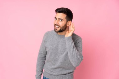 Kafkasyalı yakışıklı adam izole edilmiş arka planda bir şeyler dinlerken elini kulağına koydu.