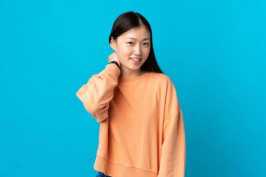 Genç Çinli kız mavi arka planda gülüyor.