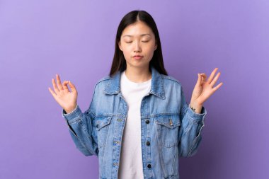 Zen pozisyonunda, izole edilmiş mor arka planı olan genç bir Çinli kız.