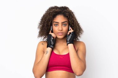 Genç Afrikalı Amerikalı spor kadın beyaz arka planda izole edilmiş müzik dinliyor ve ön tarafa bakıyordu.