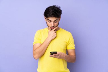 Arap yakışıklı bir adam soyutlanmış arka planda düşünüyor ve mesaj gönderiyor.