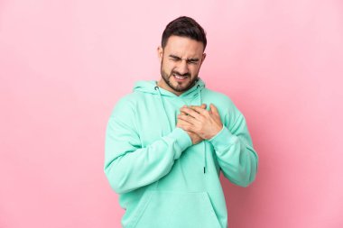 Pembe arka planda izole edilmiş beyaz tenli yakışıklı bir adamın kalbinde bir ağrı var.