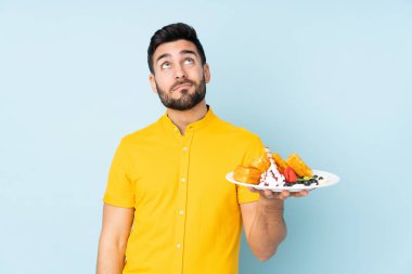 Beyaz adam mavi arka planda gözleme tutuyor.