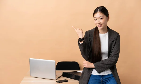 Chinese business woman in her workplace pointing finger to the side