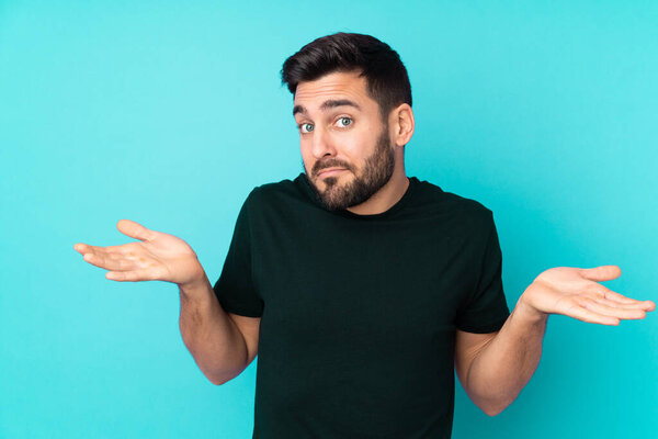 Caucasian handsome man isolated on blue background having doubts while raising hands