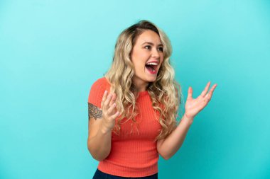 Genç Brezilyalı bir kadın mavi arka planda izole edilmiş ve yüzünde sürpriz bir ifade var.