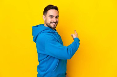 Sarı arka planda izole edilmiş beyaz, yakışıklı genç bir adam.