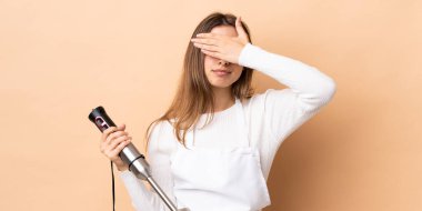 El blenderi kullanan bir kadın izole edilmiş arka planda gözlerini elleriyle kapatıyor. Bir şey görmek istemiyorum.