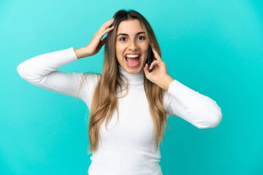 Mavi arka planda izole edilmiş cep telefonu kullanan beyaz bir kadın.