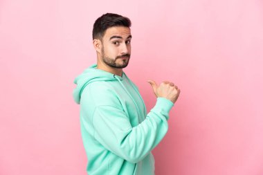 Beyaz tenli yakışıklı adam pembe arka planda soyutlanmış gururlu ve kendini beğenmiş.