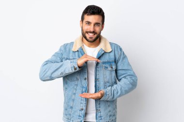 Beyaz arka planda sakallı yakışıklı genç bir adam. Bir ilan vermek için avucunda hayali bir şey tutuyor.