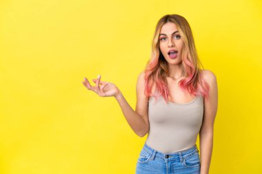 İzole edilmiş sarı arka planda genç bir kadın şüpheli hareketler yapıyor.