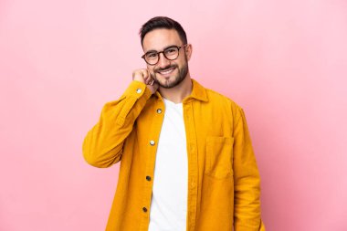 Beyaz tenli yakışıklı adam pembe arka planda izole edilmiş gülüyor.