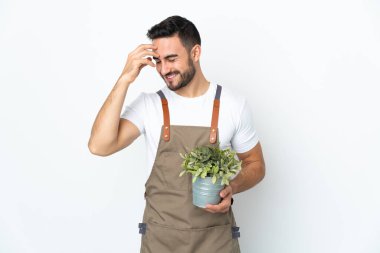 Bahçıvan elinde bir bitki tutuyor. Beyaz arka planda izole edilmiş. Gülüyor.