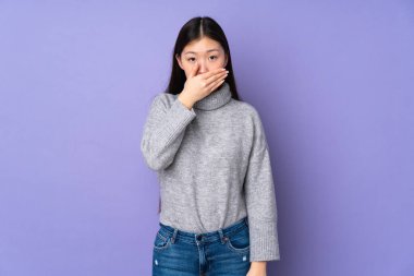 Asyalı genç bir kadın izole edilmiş arka planda ağzı elle kapatıyor.