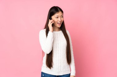 Asyalı genç bir kadın izole edilmiş arka planda cep telefonuyla sohbet ediyor.