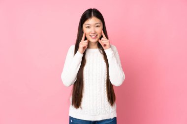 Asyalı genç bir kadın izole edilmiş, mutlu ve hoş bir ifadeyle gülümsüyor.