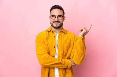 Pembe arka planda izole edilmiş genç beyaz yakışıklı adam mutlu ve yukarıya bakıyor.