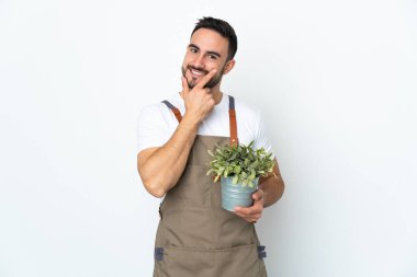 Bahçıvan elinde çiçekle beyaz arka planda mutlu ve gülümsüyor.