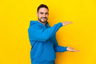 Beyaz tenli yakışıklı, sarı arka planda izole edilmiş. Kopyalama alanı var.