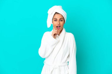 İzole edilmiş mavi arka planda bornozlu genç bir kadın parmağını kaldırarak çözümü bulmaya çalışıyor.