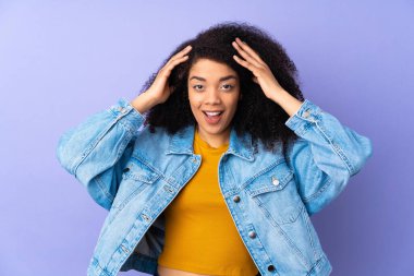 Genç Afrikalı Amerikalı kadın, mor arka planda, sürpriz bir ifadeyle izole edilmiş.