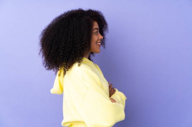 Genç Afrikalı Amerikalı kadın, mor arka planda, yan pozisyonda izole edilmiş.