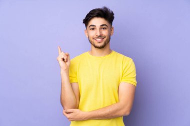 Münzevi geçmişi olan yakışıklı Arap bir adam mutlu ve yukarıya bakıyor.