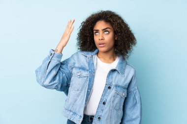 Genç Afrikalı Amerikalı kadın mavi arka planda izole edilmiş, yorgun ve hasta bir ifadeyle.