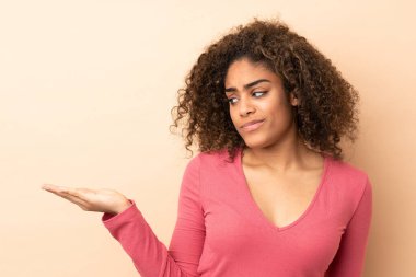 Genç Afrikalı Amerikalı kadın bej arka planda izole edilmiş.